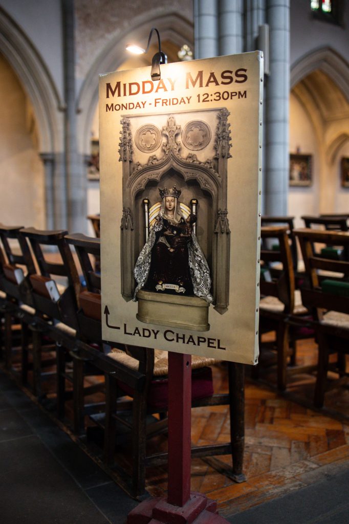 Sign for Midday Mass at church entrance