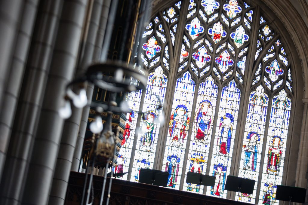 Stained-glass east window above the sanctuary, depicting saints in vibrant coloured glass.